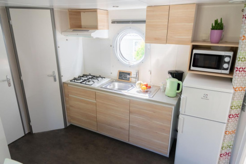 Cocina luminosa en Mobile Home «ECO Lodgia» en Flower Camping Provence Vallée, con estufa y equipamiento moderno.