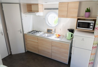 Cuisine lumineuse du Mobile Home «ECO Lodgia» au Flower Camping Provence Vallée, avec cuisinière et équipements modernes.
