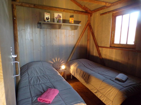 Innenansicht des Lodgehut op palen Baumhauses mit zwei Einzelbetten bei Flower Camping Provence Vallée in Frankreich.