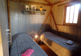 Intérieur du Lodgehut op palen avec deux lits simples au Flower Camping Provence Vallée, en France.