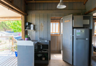 Interior view of a treehouse kitchen with fridge, sink, and coffeemaker at Flower Camping Provence Vallée.