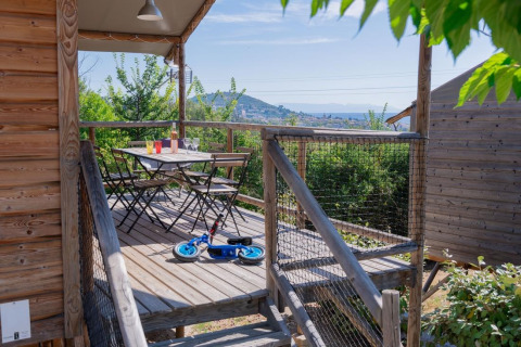 Træhytte terrasse med bord, stole og løbecykel på Flower Camping Provence Vallée i Frankrig.