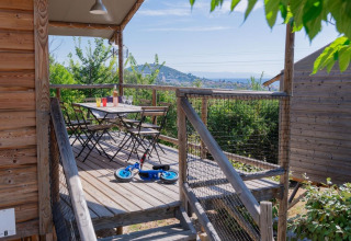 Træhytte terrasse med bord, stole og løbecykel på Flower Camping Provence Vallée i Frankrig.