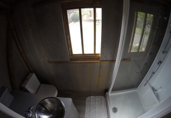 Salle de bain dans une cabane perchée avec toilettes, lavabo et douche à Lodgehut op palen, Flower Camping Provence Vallée.