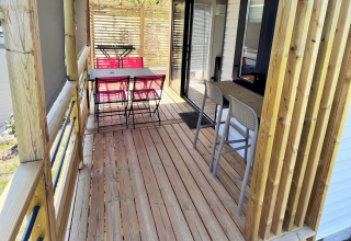 Terrazza in legno coperta con tavolo da pranzo al Mobile Home «Living» presso Flower Camping Provence Vallée, Francia.