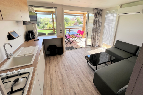 Moderne mobilhomeindretning med køkken, stue og terrasseudsigt hos Flower Camping Provence Vallée, Frankrig.