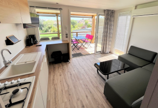 Intérieur de mobil-home moderne avec cuisine, salon et terrasse au Flower Camping Provence Vallée, France.