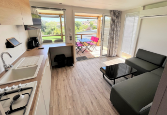 Moderne mobilhomeindretning med køkken, stue og terrasseudsigt hos Flower Camping Provence Vallée, Frankrig.