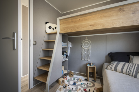 Habitación infantil moderna en Mobile Home Living en Flower Camping Provence Vallée con litera y alfombra de juegos.