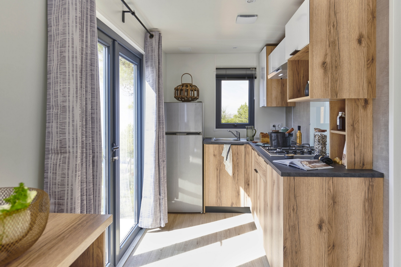 Moderne keuken met houten kasten en grote ramen in Mobile Home «New Horizon» bij Flower Camping Provence Vallée.