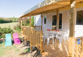 Mobilhytte med træterrasse, hvide havemøbler og solsenge på Flower Camping Provence Vallée i Frankrig.