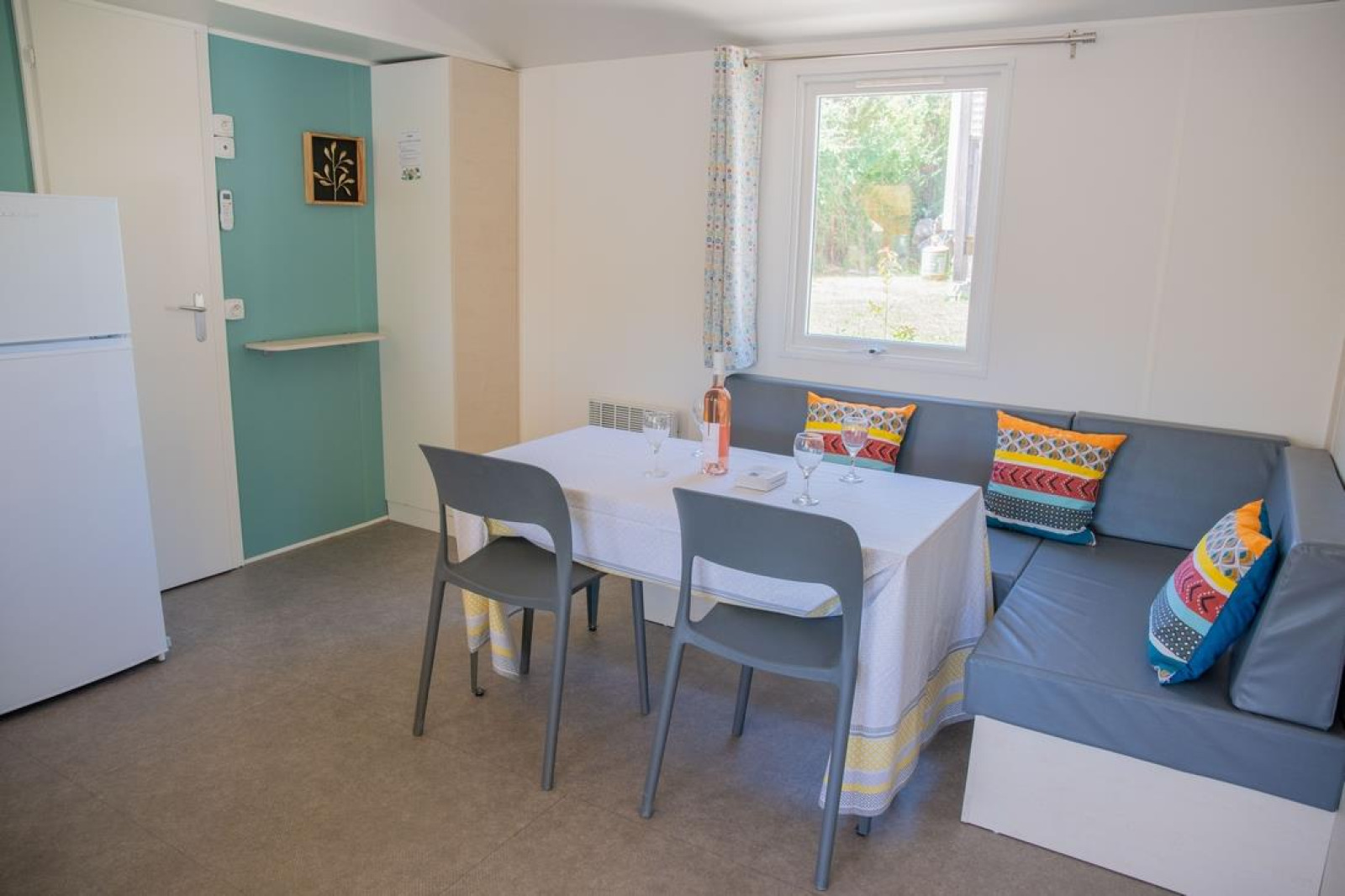 Eethoek in Mobile Home «Tribu» op Flower Camping Provence Vallée in Frankrijk met een hoekbank en gekleurde kussens.