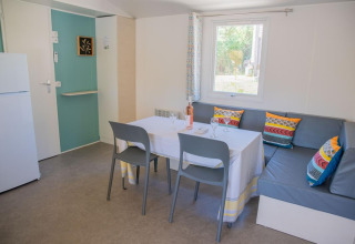Zona pranzo nella Mobile Home «Tribu» presso Flower Camping Provence Vallée in Francia, con divano ad angolo e cuscini colorati.