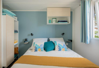 Soveværelse i Mobile Home «Tribu» på Flower Camping Provence Vallée i Frankrig med blåt og hvidt interiør.
