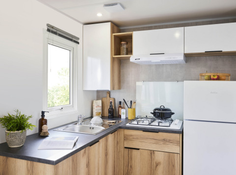 Cucina moderna in una Premium Mobile Home con mobili in legno, fornello a gas e frigo al Flower Camping Provence Vallée.