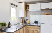 Moderne keuken in een Premium Mobile Home met houten kasten, gaskookplaat en koelkast bij Flower Camping Provence Vallée.