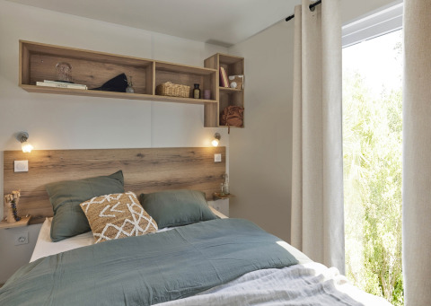 Premium Mobile Home soveværelse med træpanel, grøn dyne, vindue og hylder, Flower Camping Provence Vallée.