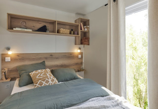 Dormitorio de Premium Mobile Home en Flower Camping Provence Vallée con detalles en madera y ropa de cama verde.