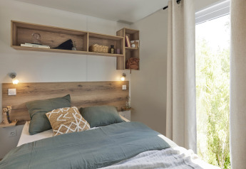 Premium Mobile Home bedroom at Flower Camping Provence Vallée, wood accents, green bedding, shelves, window.