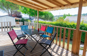 Überdachte Holzterrasse mit bunten Stühlen und Tisch im Premium Mobile Home bei Flower Camping Provence Vallée.