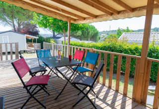 Terrasse en bois couverte avec chaises colorées et table au Premium Mobile Home à Flower Camping Provence Vallée, France.