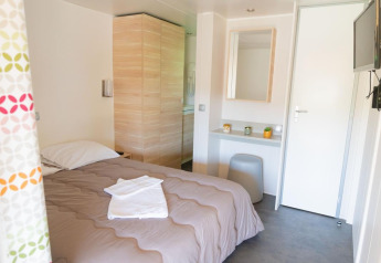 Premium Mobile Home met 2 slaapkamers in Flower Camping Provence Vallée, lichte kamer met bed en tv.