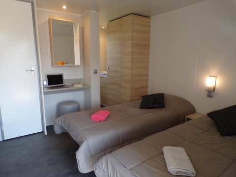 Casa mobile premium con due letti singoli, scrivania, armadio e luci accoglienti presso Provence Vallée.