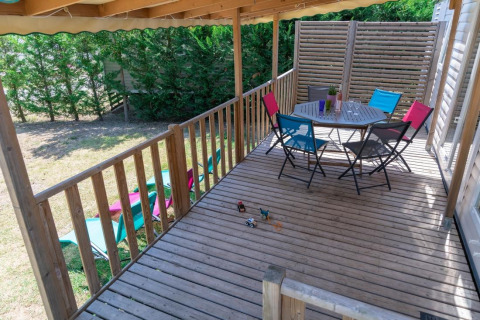 Terraza de madera con sillas coloridas en Premium Mobile Home de Flower Camping Provence Vallée en Francia.