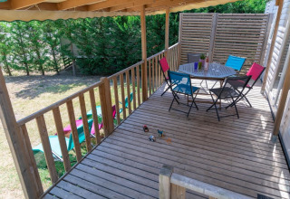 Terrazza in legno con tavolo e sedie colorate al Premium Mobile Home al Flower Camping Provence Vallée, Francia.