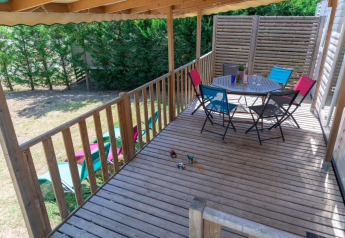 Holzterrasse mit bunten Stühlen und Tisch im Premium Mobile Home bei Flower Camping Provence Vallée, Frankreich.