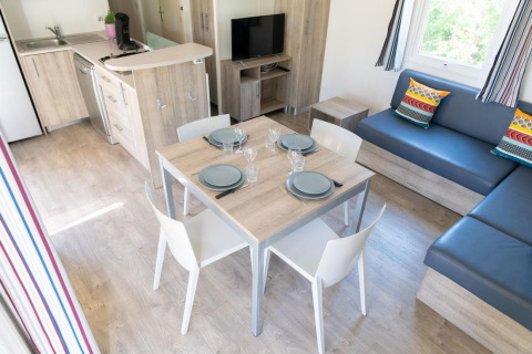 Modern living area and kitchen in Premium Mobile Home with dining table, sofa and colorful cushions.