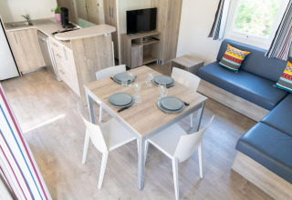 Salon moderne et cuisine du Premium Mobile Home avec table à manger, canapé et coussins colorés.