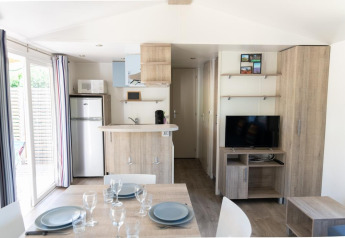 Interno luminoso di una Casa Mobile Premium con angolo cottura, tavolo da pranzo e TV al Flower Camping Provence Vallée.