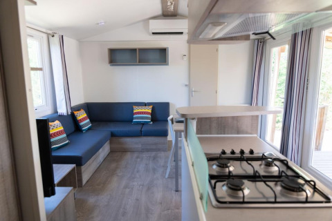 Indvendigt billede af Premium Mobile Home med stue, køkken og farverige puder i Provence Vallée, Frankrig.