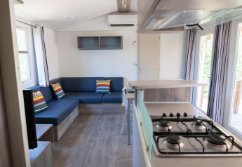 Innenaufnahme des Premium Mobile Home mit moderner Küche, Sitzecke und bunten Kissen in Provence Vallée.
