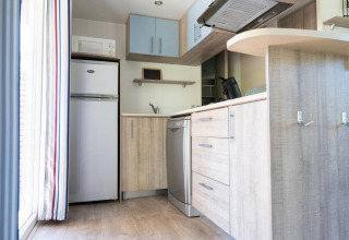 Moderne kitchenette met koelkast, vaatwasser en houten kasten in een mobilhome in de Provence, Frankrijk.