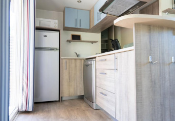 Moderne kitchenette met koelkast, vaatwasser en houten kasten in een mobilhome in de Provence, Frankrijk.