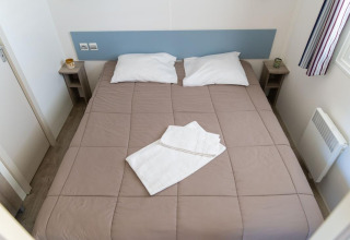 Premium Mobile Home bedroom with double bed, two pillows, towels and nightstands at Flower Camping Provence Vallée.