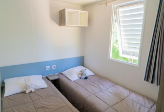 Slaapkamer in Premium Mobile Home bij Flower Camping Provence Vallée met twee enkele bedden en knuffeldieren.
