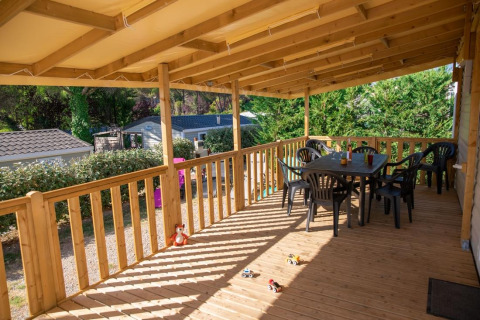Veranda in legno coperta al Premium Mobile Home presso Flower Camping Provence Vallée, con tavolo e sedie.