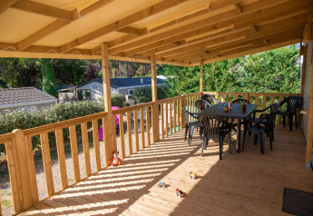Terraza de madera cubierta en Premium Mobile Home en Flower Camping Provence Vallée, con mesa y sillas.