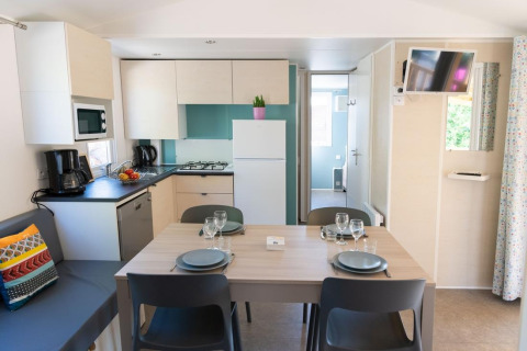Interior of a Premium Mobile Home featuring a full kitchen and dining setup at Provence Vallée in France.
