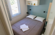 Camera da letto in una Premium Mobile Home con letto matrimoniale, finestra e arredo moderno al Flower Camping Provence Vallée.