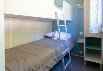 Camera moderna con letto a castello, coperta grigia e peluche al Flower Camping Provence Vallée, Francia.