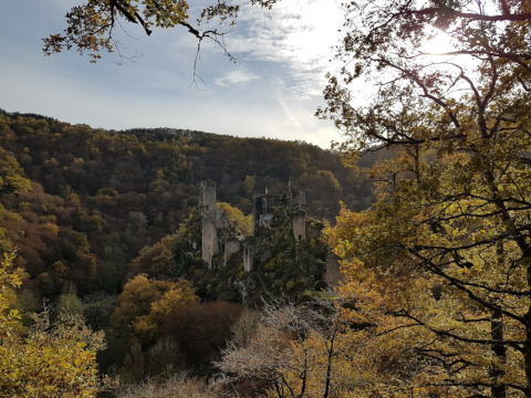 View of a medieval castle ruin surrounded by autumn forest at Seasonova Lac de Bournazel in Nouvelle-Aquitaine.