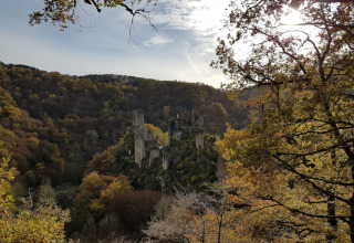 Vista su rovine di un castello medievale circondato da foresta autunnale a Seasonova Lac de Bournazel, Francia.