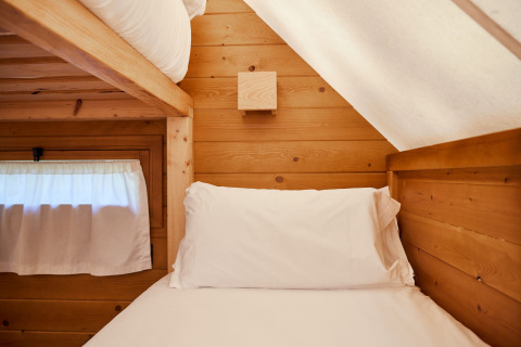 Knus slaaphoekje in de Janda tent van TAIGA Tarifa, Spanje, met houten wanden en een eenpersoonsbed.