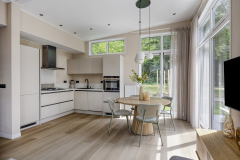 Modern kitchen and dining area with large windows in Heidehof lodge at Forest Park Ede, Netherlands.