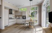 Modern kitchen and dining area with large windows in Heidehof lodge at Forest Park Ede, Netherlands.