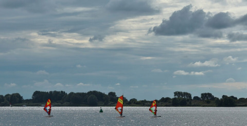 Windsurfer sull'acqua presso il campeggio de Haas a Zeeland, Paesi Bassi, sotto un cielo nuvoloso.